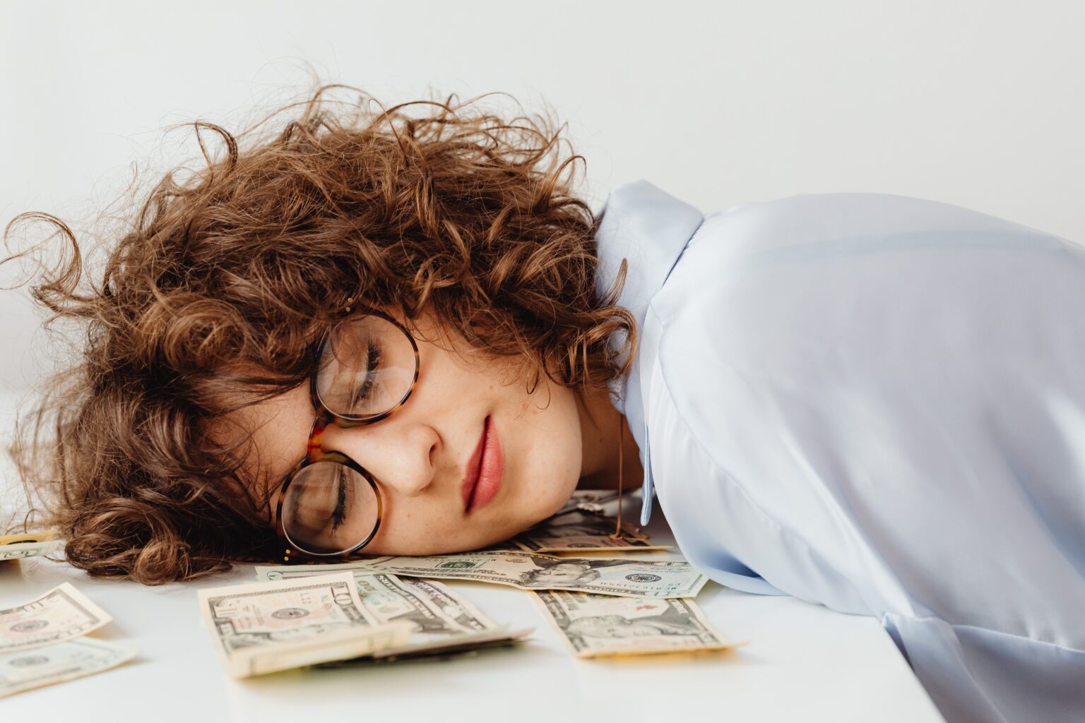 Woman asleep on desk with money underneath her