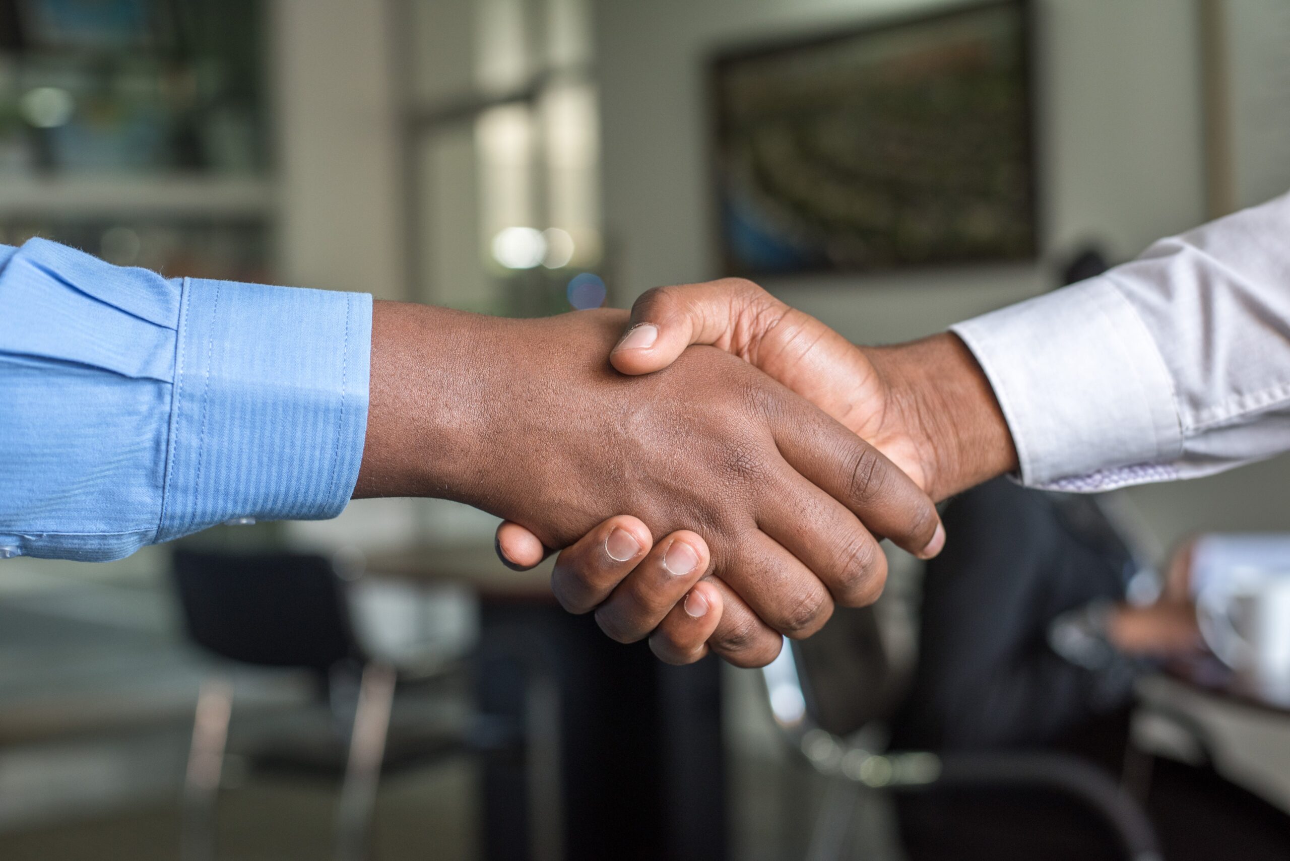 two hands shaking in front of an office background