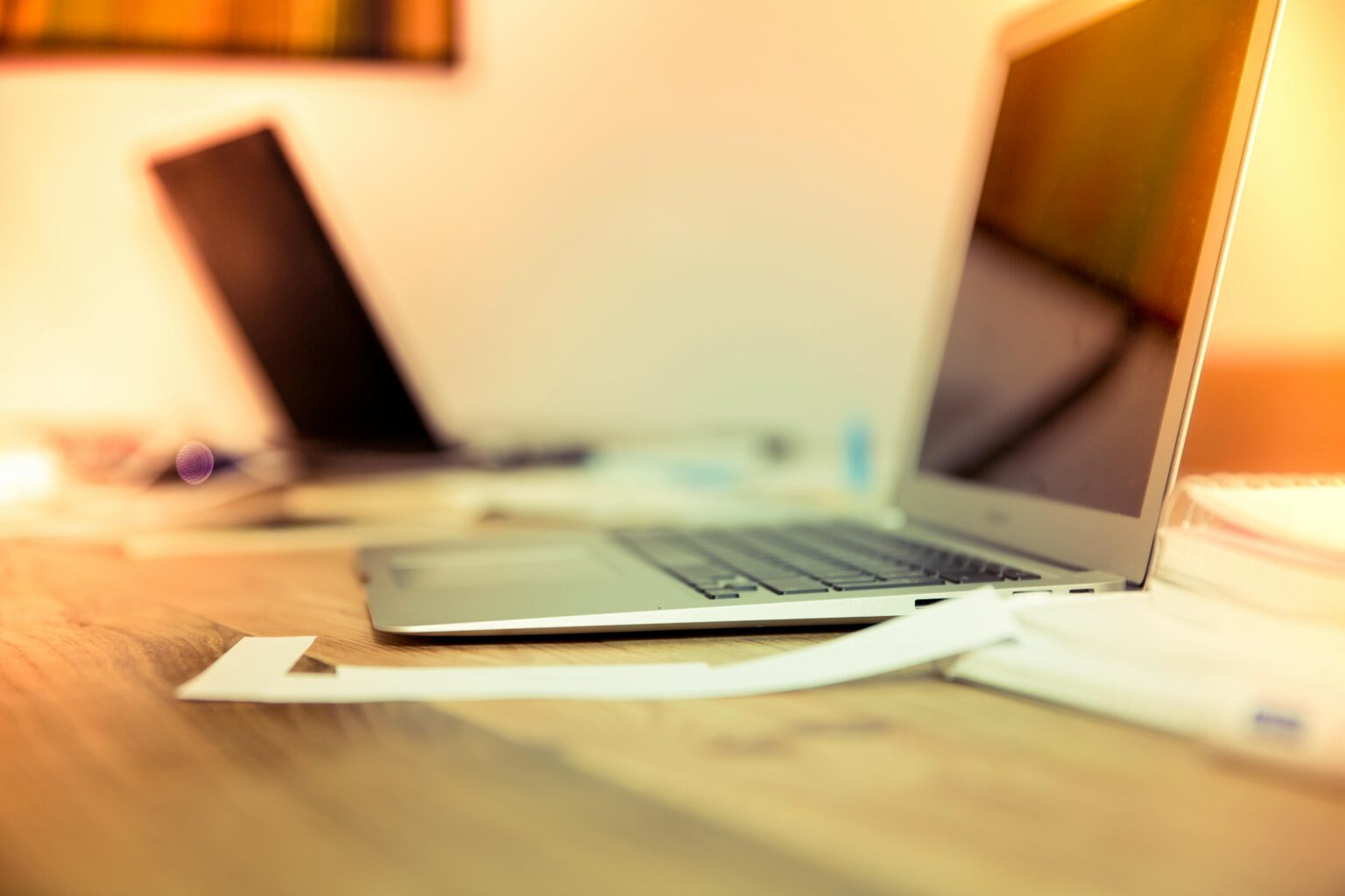 two laptops sitting on a desk, all out of focus