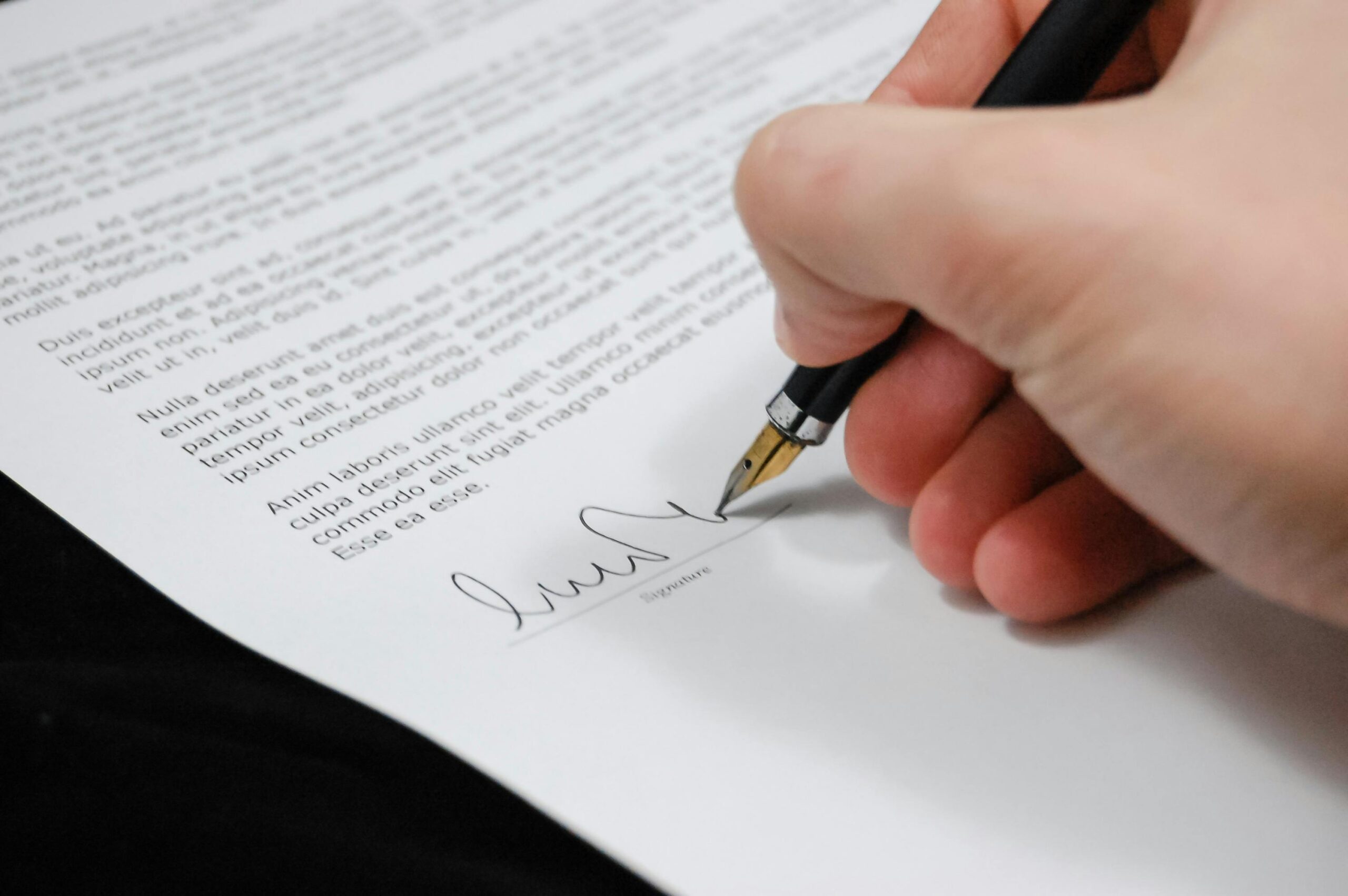 hand signing legal document with calligraphy pen