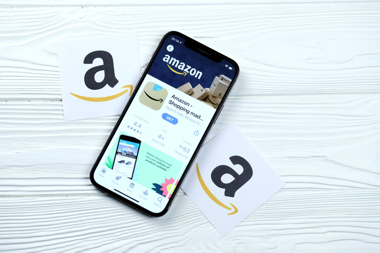 Amazon icon and application from App store on iPhone 12 pro display screen on white wooden table