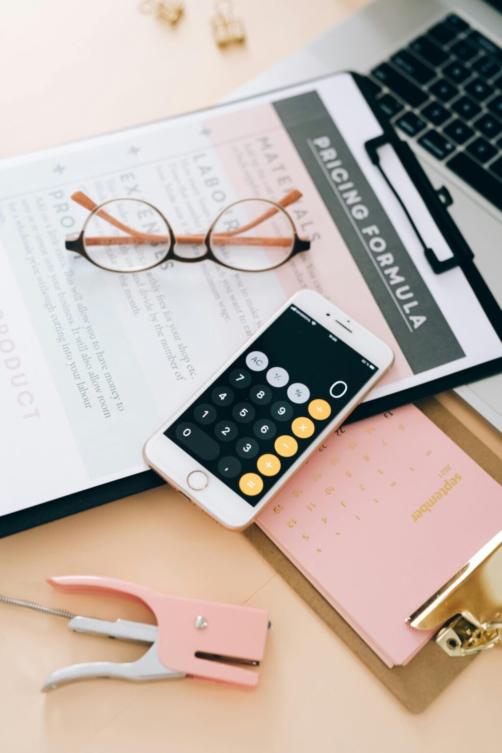 minimum advertised price on Amazon sheet with calculator on phone, glasses on top, scattered office tools