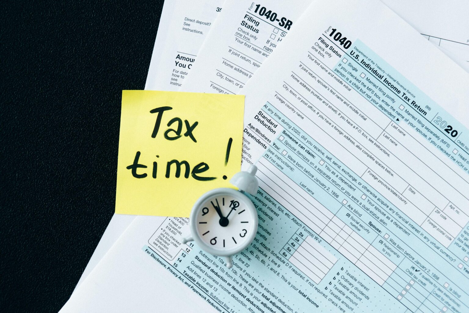 tax forms with a yellow sticky note on top that says "Tax time!"